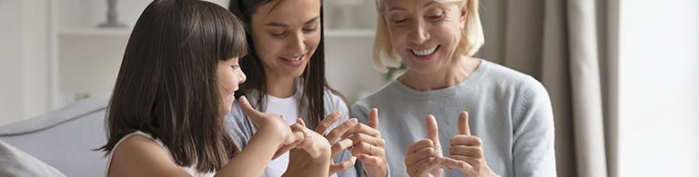 zwei Mädchen und eine Seniorin üben Gebärden
